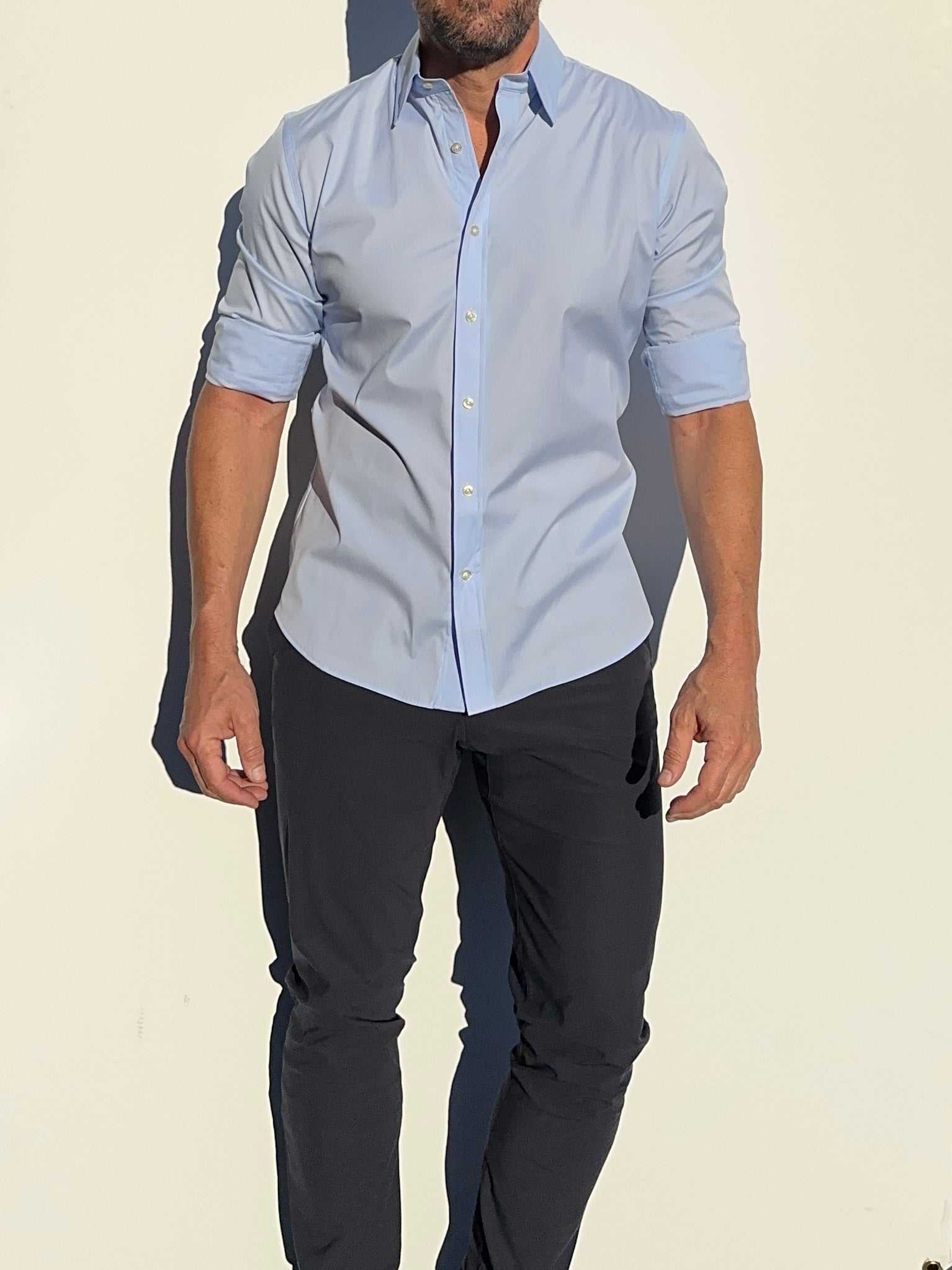 A model wearing a long-sleeved light blue dress shirt with a collar, button-up shirt.