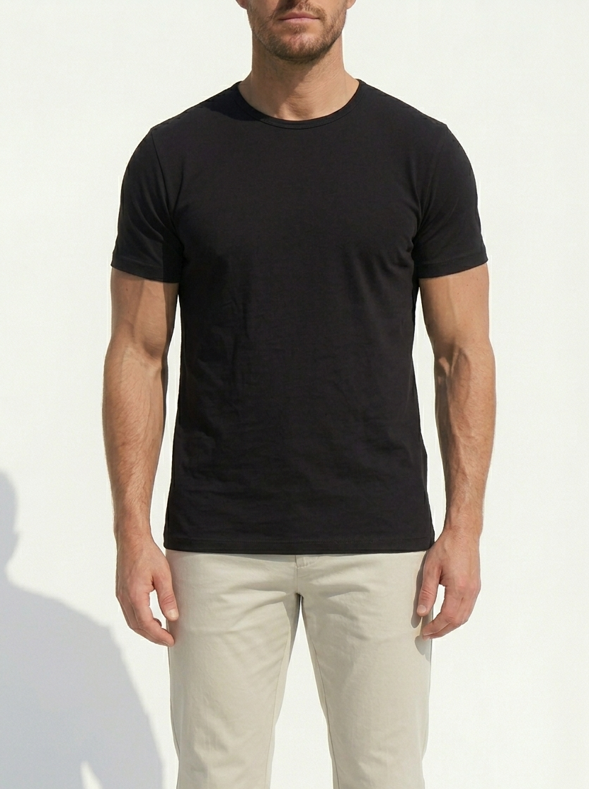 Man wearing a black t-shirt and light-colored pants against a white background