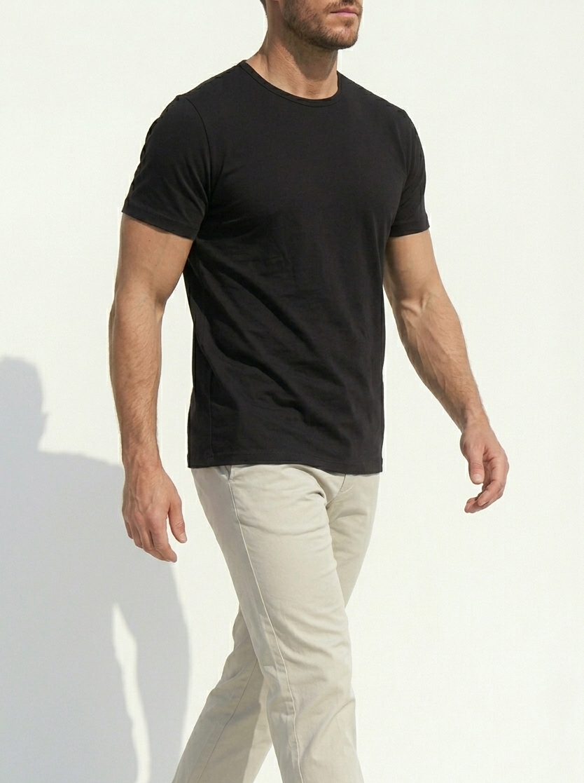 Man wearing a black t-shirt and beige pants against a white background
