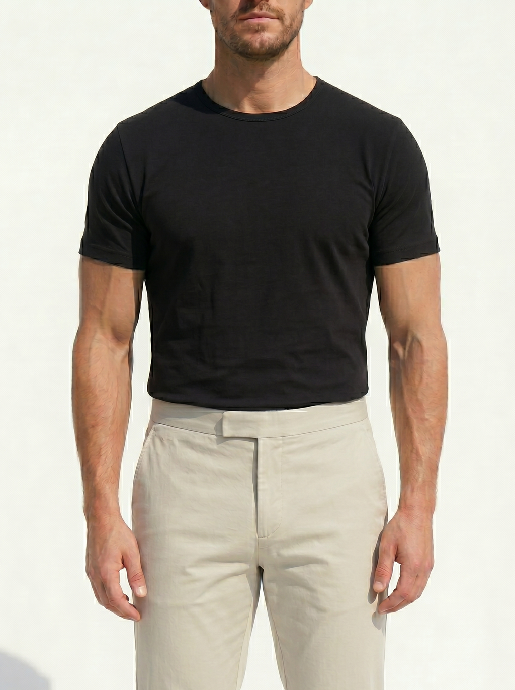 Man wearing a black t-shirt and beige pants on a white background