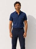 Man wearing a blue short-sleeve shirt and dark pants against a white background