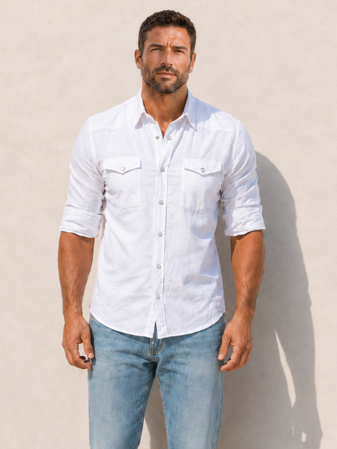 Man wearing a white shirt and light blue jeans against a beige wall.