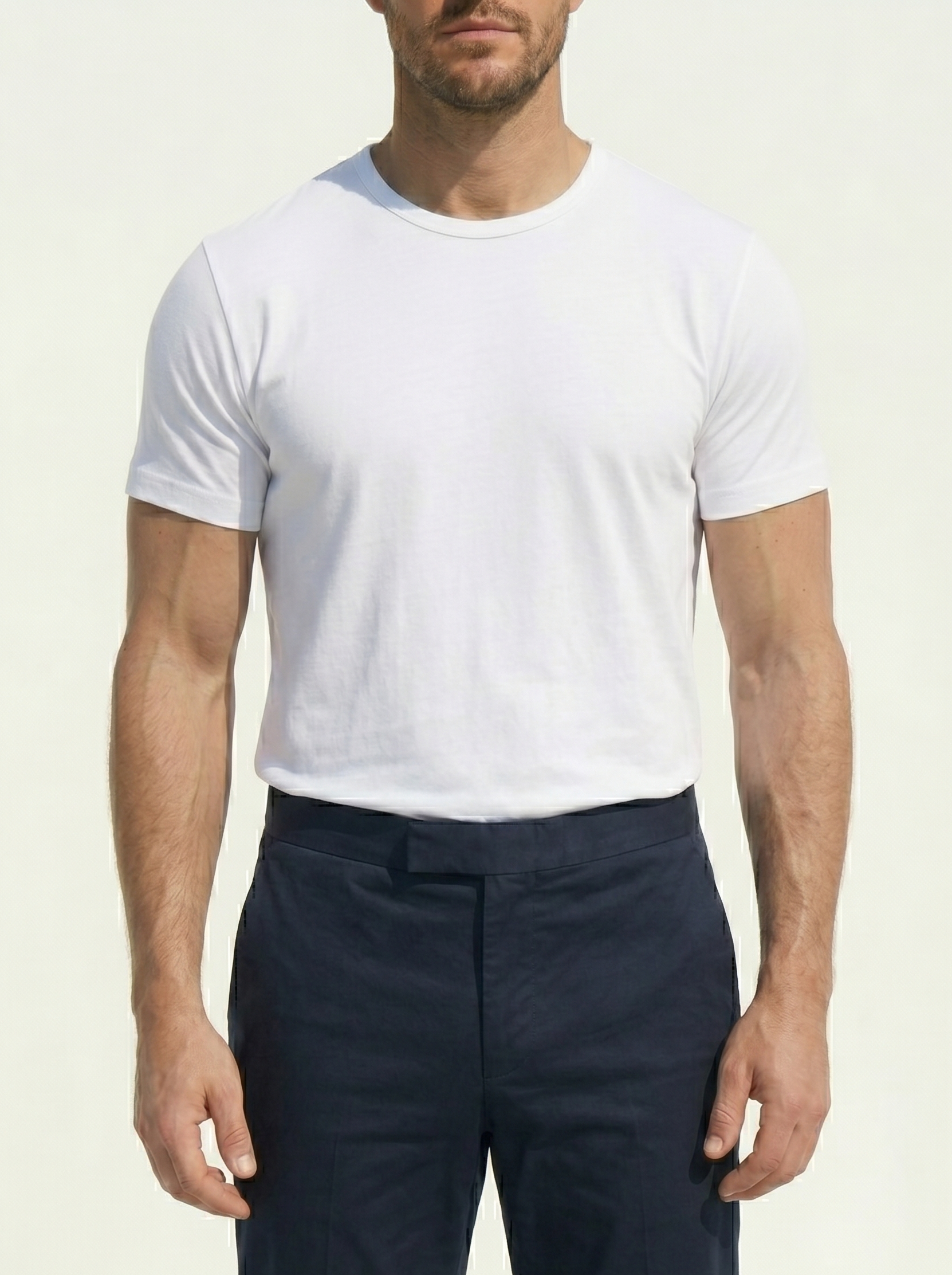 Man wearing a white t-shirt and navy pants on a plain background